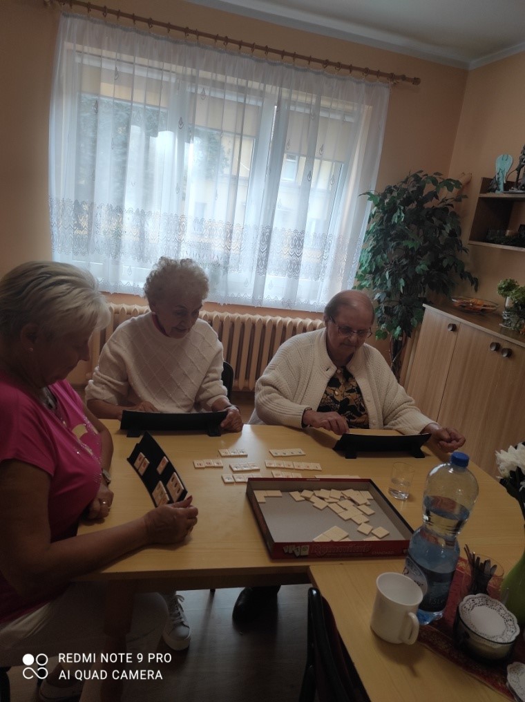 trzy kobiety w pomieszczeniu, siedzą przy stole przy grze scrable